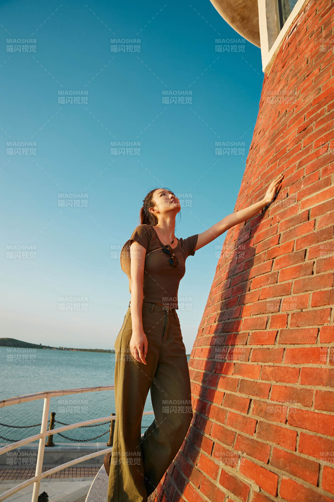 盛夏夕阳晚霞湖边码头灯塔上的少女图片