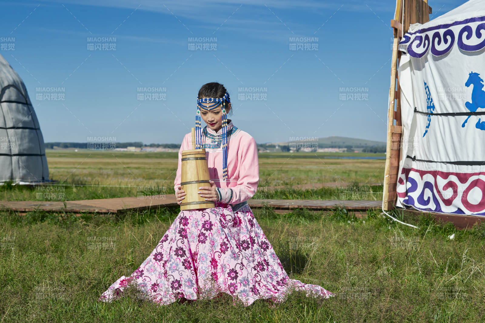 蒙古包前穿蒙古族饰怀抱奶茶桶的蒙族少女图片