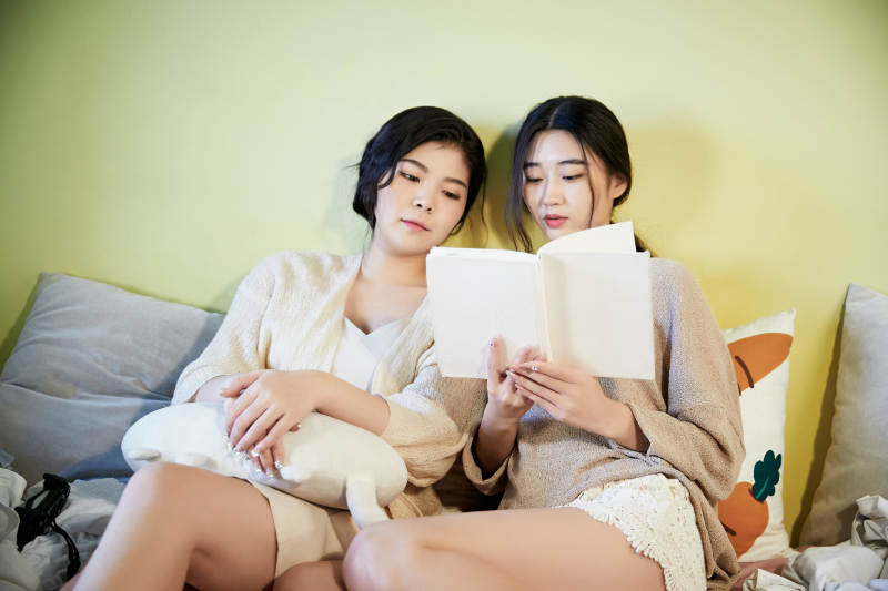 坐在床上读书的俩位美女图片