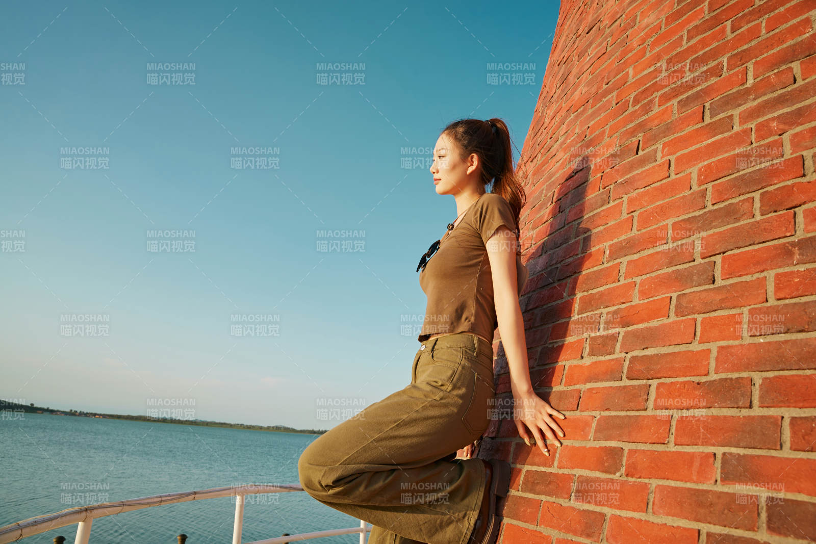 盛夏夕阳晚霞湖边码头灯塔上的少女图片