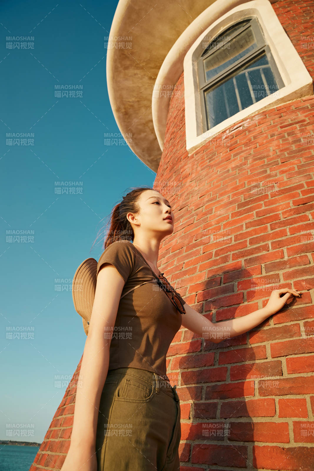 盛夏夕阳晚霞湖边码头灯塔上的少女图片