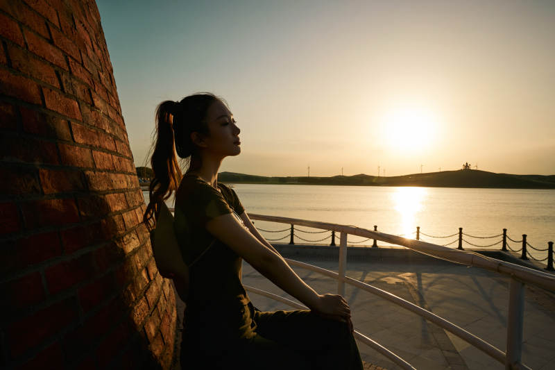 盛夏夕阳晚霞湖边码头灯塔上的少女图片