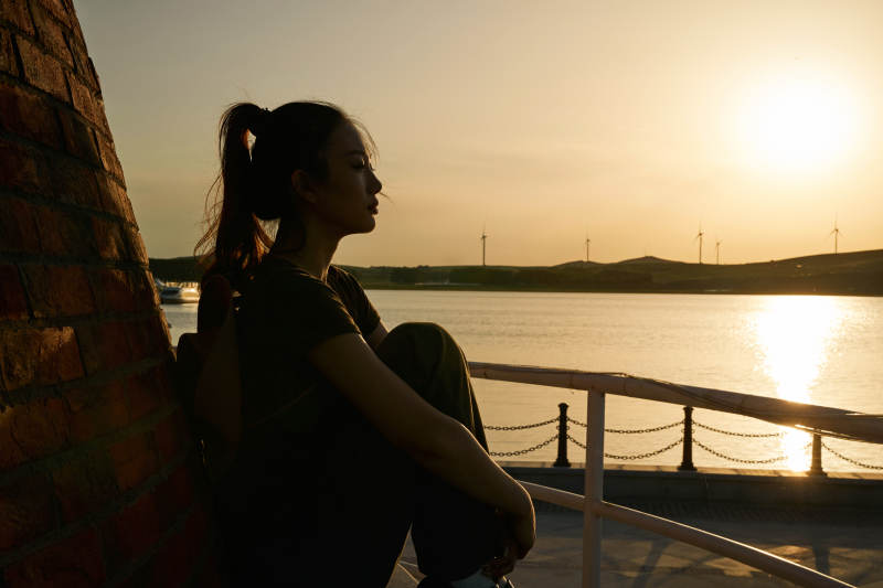 盛夏夕阳晚霞湖边码头灯塔上的少女图片