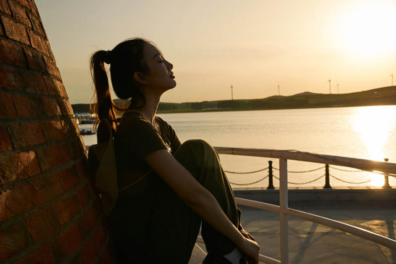 盛夏夕阳晚霞湖边码头灯塔上的少女图片