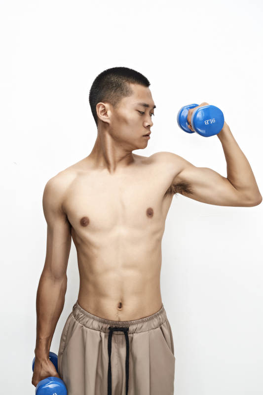 使用哑铃进行健身锻炼的亚洲男性图片