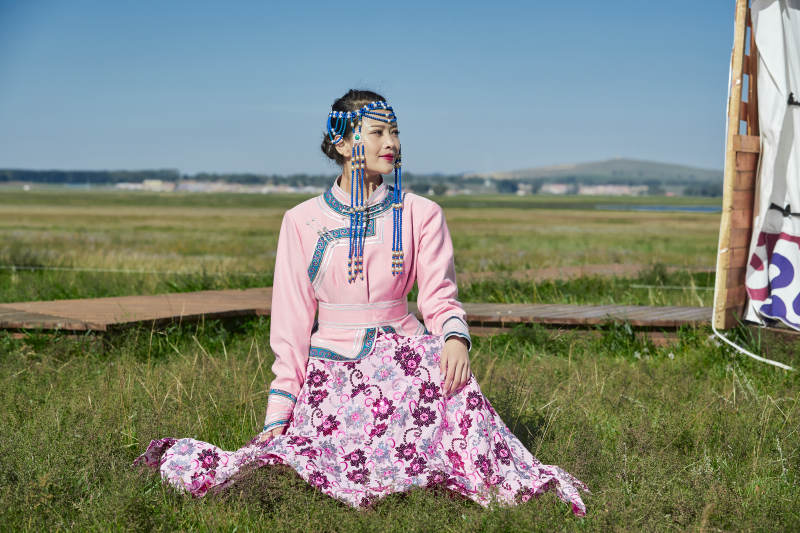 蒙古包前穿蒙古族饰怀抱奶茶桶的蒙族少女图片