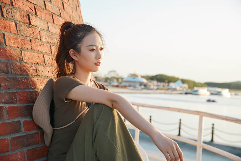 盛夏夕阳晚霞湖边码头灯塔上的少女图片