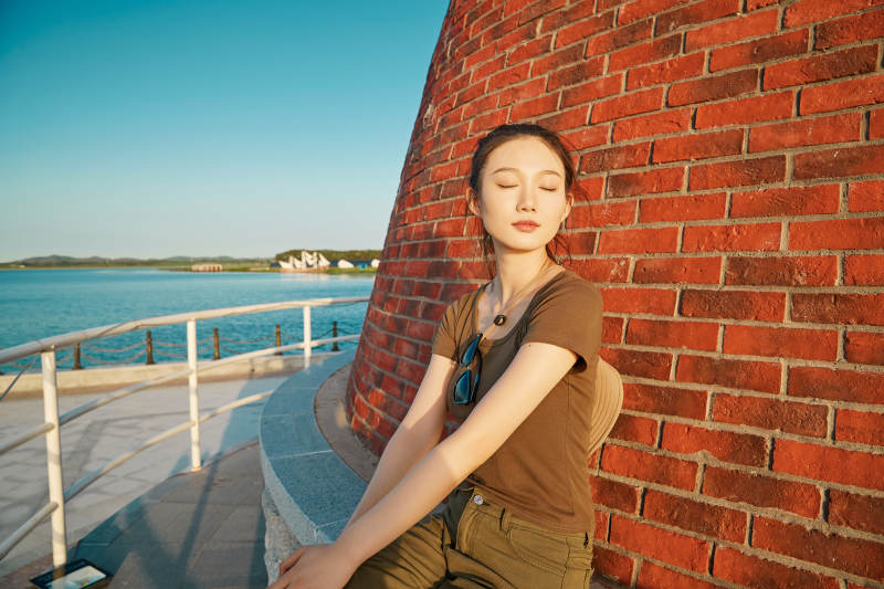 盛夏夕阳晚霞湖边码头灯塔上的少女图片