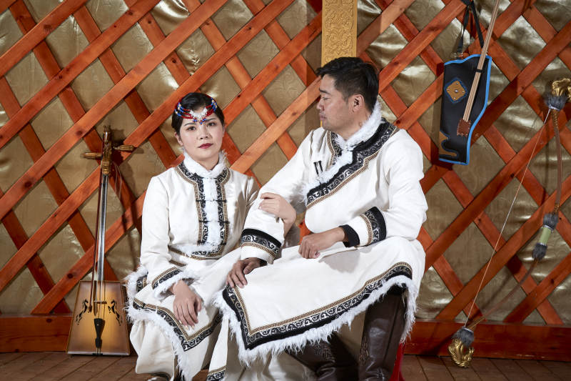 草原上蒙古包里穿蒙古族传统服饰的年轻夫妻图片