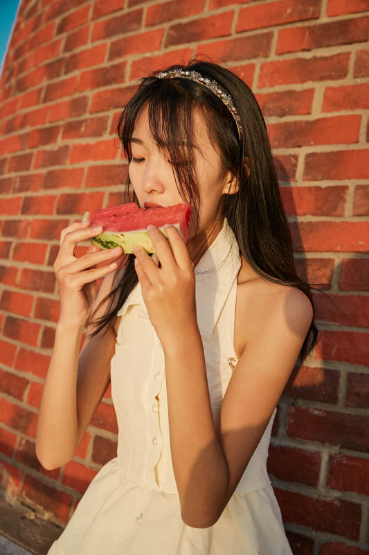 盛夏夕阳湖边码头灯塔上吃西瓜的少女图片