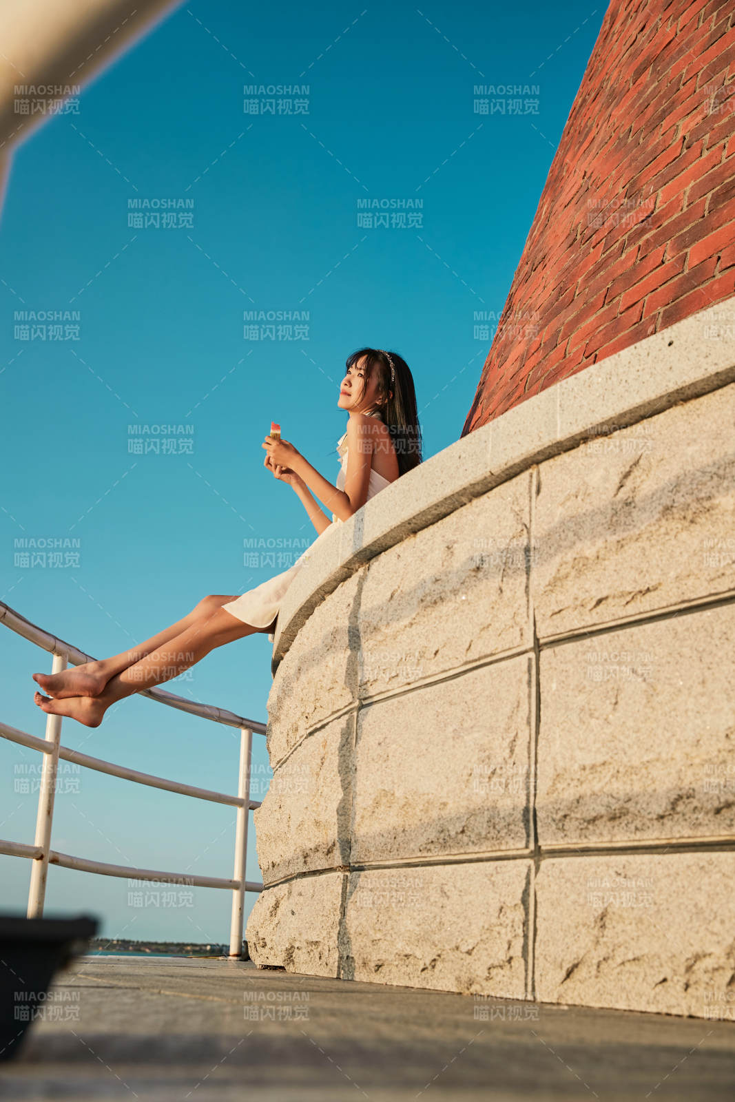 盛夏夕阳湖边码头灯塔上吃西瓜的少女图片