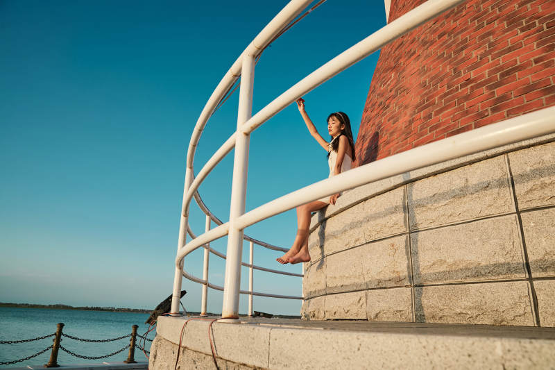 盛夏夕阳湖边码头灯塔上吃西瓜的少女图片