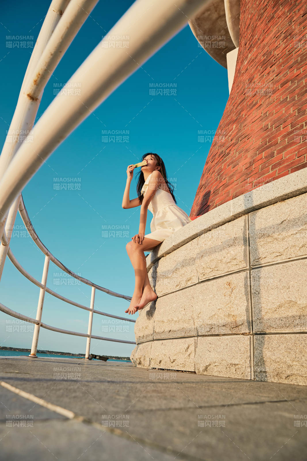 盛夏夕阳湖边码头灯塔上吃西瓜的少女图片