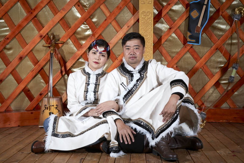 草原上蒙古包里穿蒙古族传统服饰的年轻夫妻图片