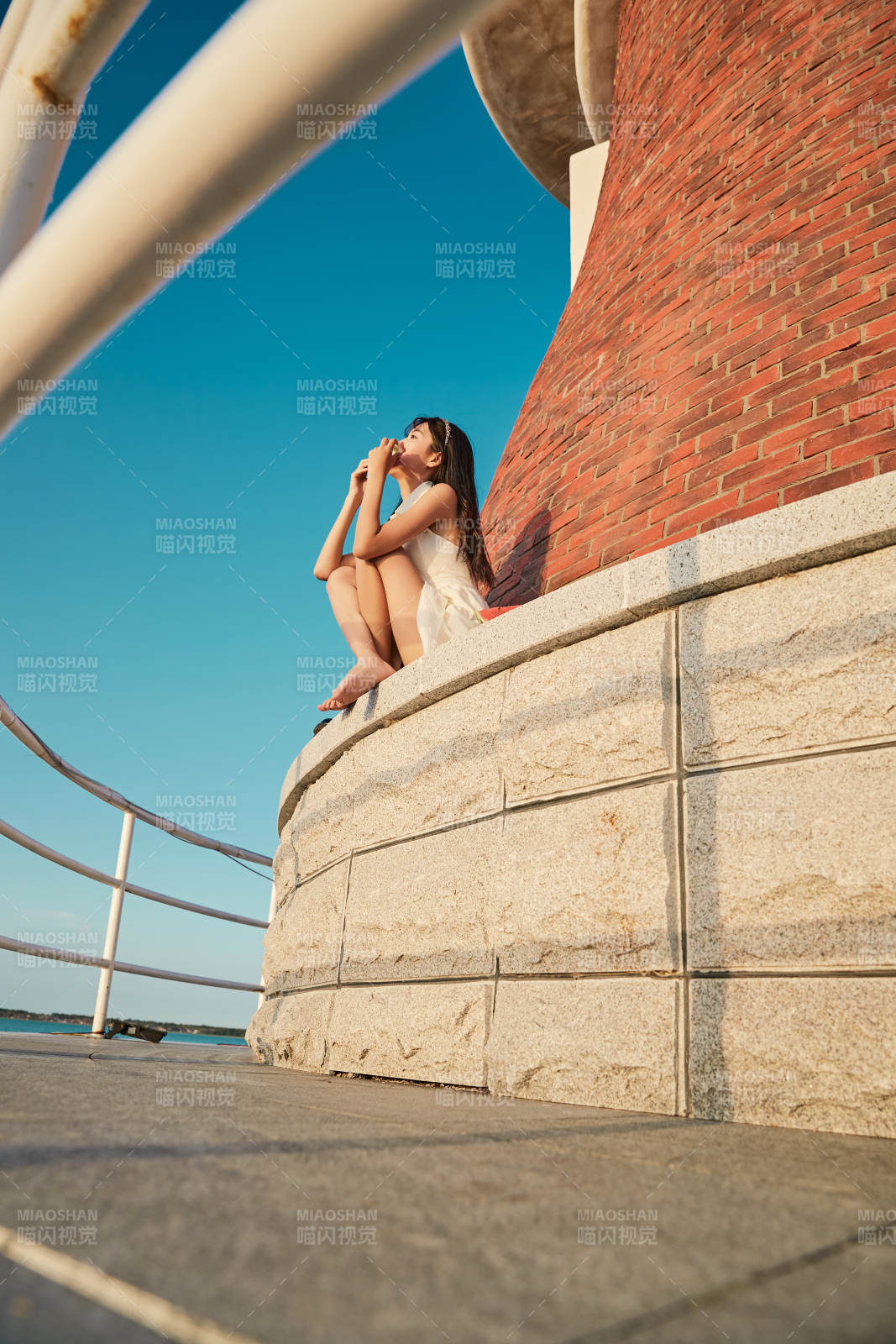 盛夏夕阳湖边码头灯塔上吃西瓜的少女图片