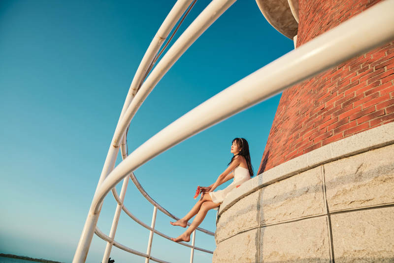 盛夏夕阳湖边码头灯塔上吃西瓜的少女图片