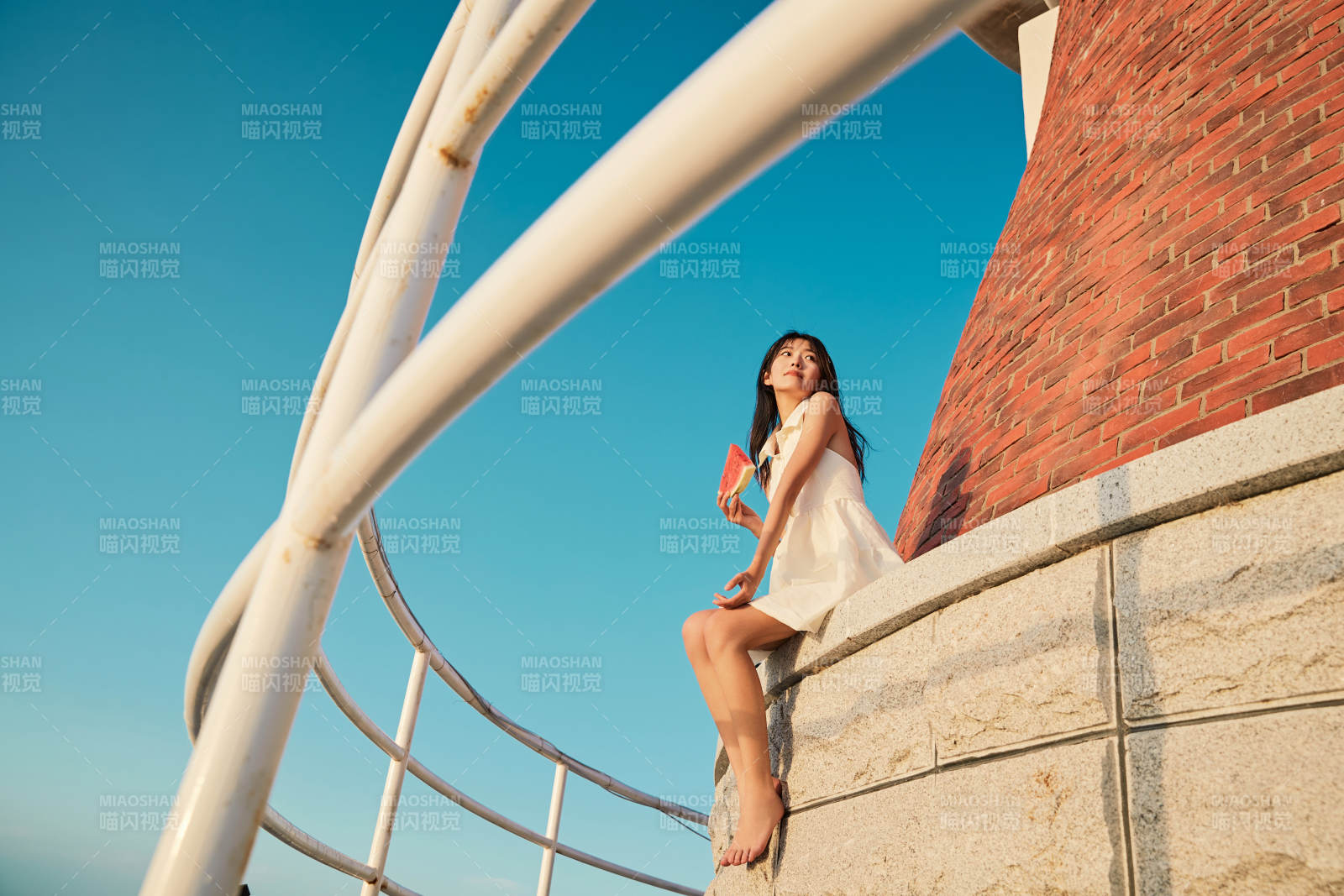 盛夏夕阳湖边码头灯塔上吃西瓜的少女图片