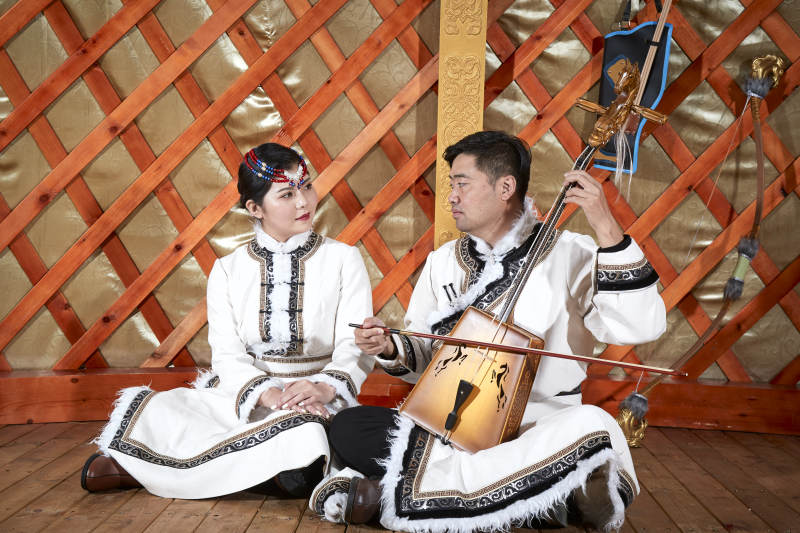 草原上蒙古包里穿蒙古族传统服饰的年轻夫妻图片