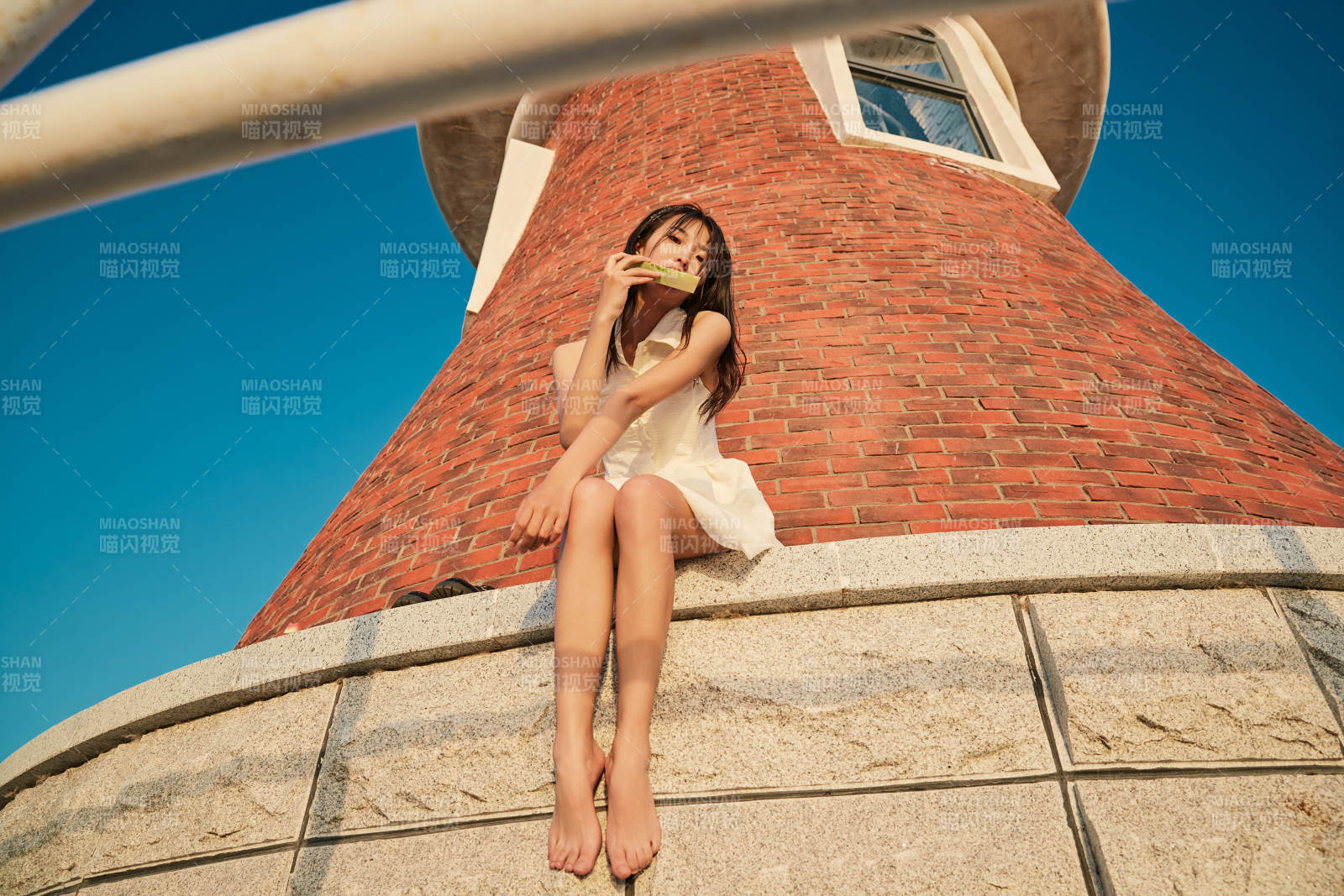 盛夏夕阳湖边码头灯塔上吃西瓜的少女图片