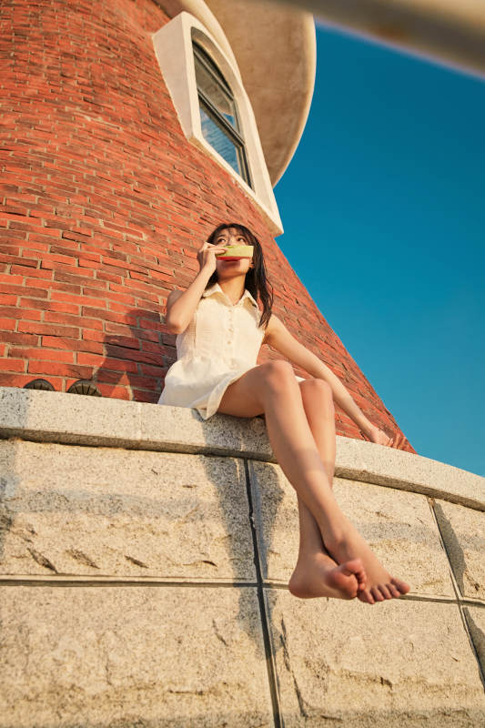 盛夏夕阳湖边码头灯塔上吃西瓜的少女图片