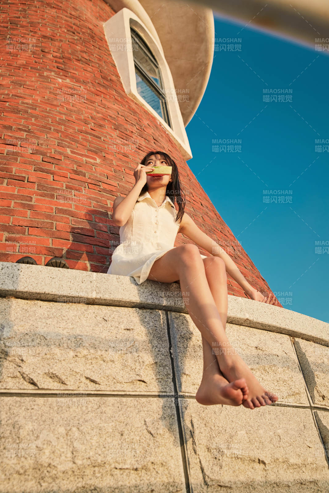 盛夏夕阳湖边码头灯塔上吃西瓜的少女图片