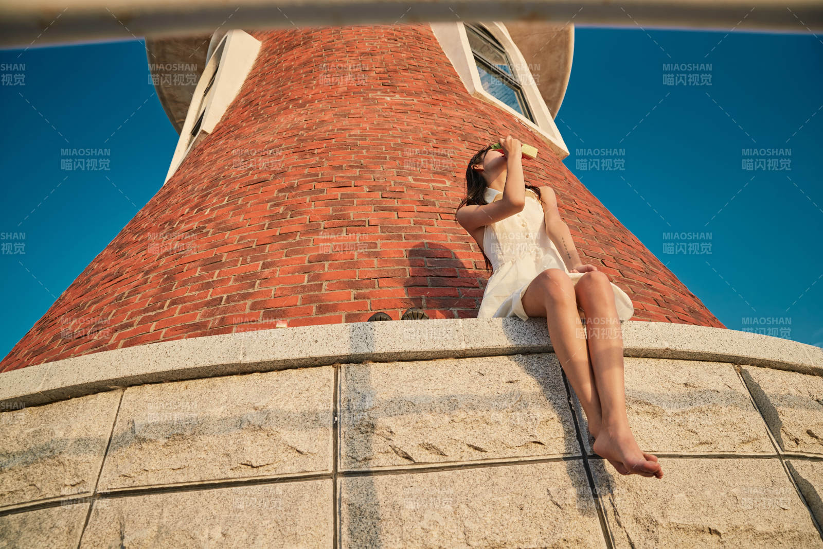 盛夏夕阳湖边码头灯塔上吃西瓜的少女图片