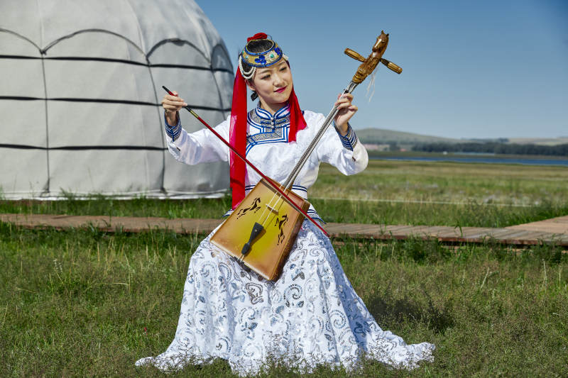 蒙古包前穿蒙古族服饰拉马头琴的蒙族女乐手图片