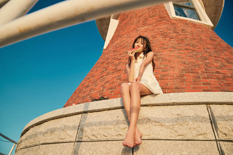 盛夏夕阳湖边码头灯塔上吃西瓜的少女图片