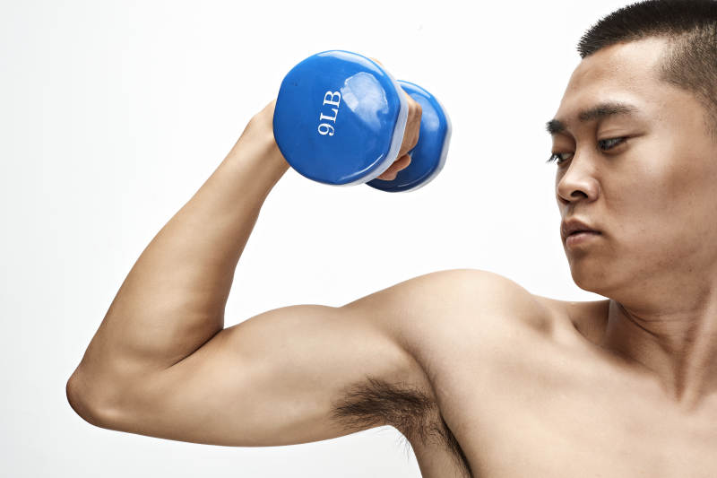 使用哑铃进行健身锻炼的亚洲男性图片