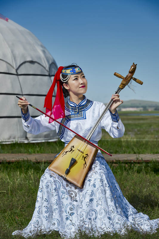 蒙古包前穿蒙古族服饰拉马头琴的蒙族女乐手图片