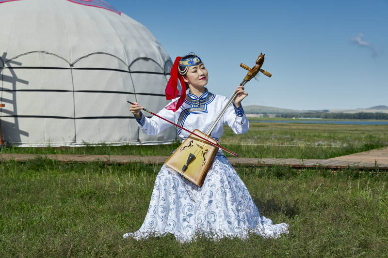 蒙古包前穿蒙古族服饰拉马头琴的蒙族女乐手图片