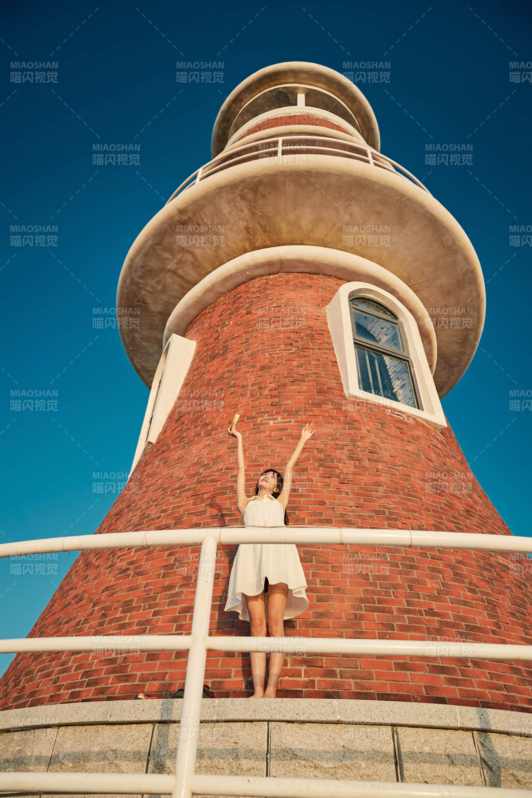 盛夏夕阳湖边码头灯塔上吃西瓜的少女图片