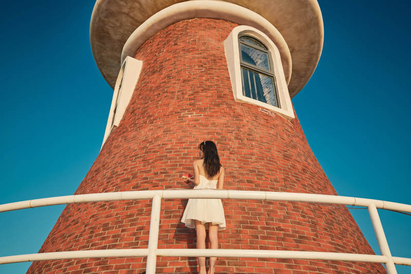 盛夏夕阳湖边码头灯塔上吃西瓜的少女图片