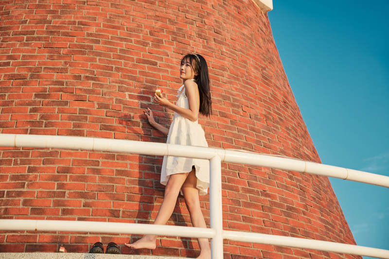 盛夏夕阳湖边码头灯塔上吃西瓜的少女图片