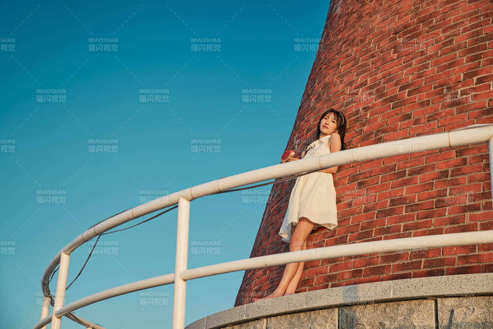 盛夏夕阳湖边码头灯塔上吃西瓜的少女图片