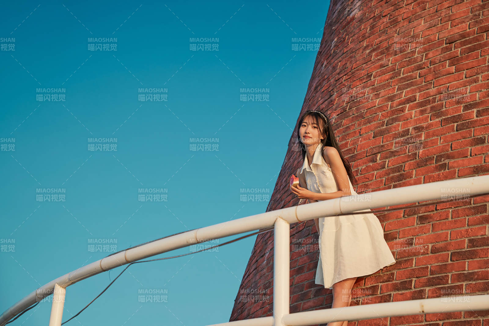 盛夏夕阳湖边码头灯塔上吃西瓜的少女图片