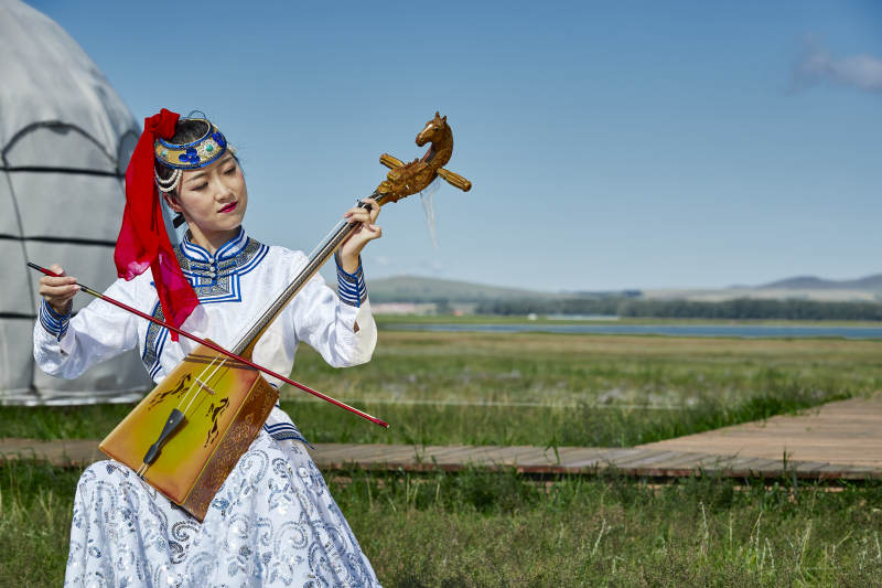 蒙古包前穿蒙古族服饰拉马头琴的蒙族女乐手图片