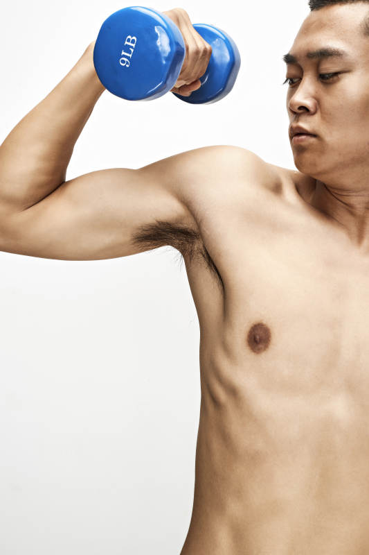 使用哑铃进行健身锻炼的亚洲男性图片