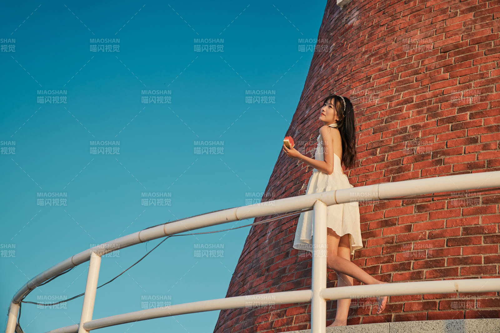 盛夏夕阳湖边码头灯塔上吃西瓜的少女图片