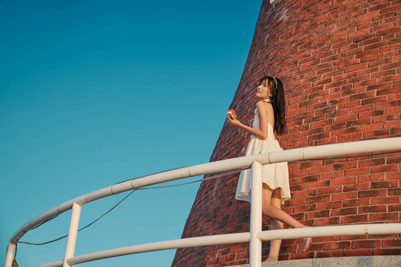 盛夏夕阳湖边码头灯塔上吃西瓜的少女图片