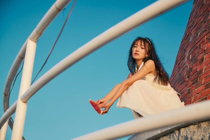 盛夏夕阳湖边码头灯塔上吃西瓜的少女图片