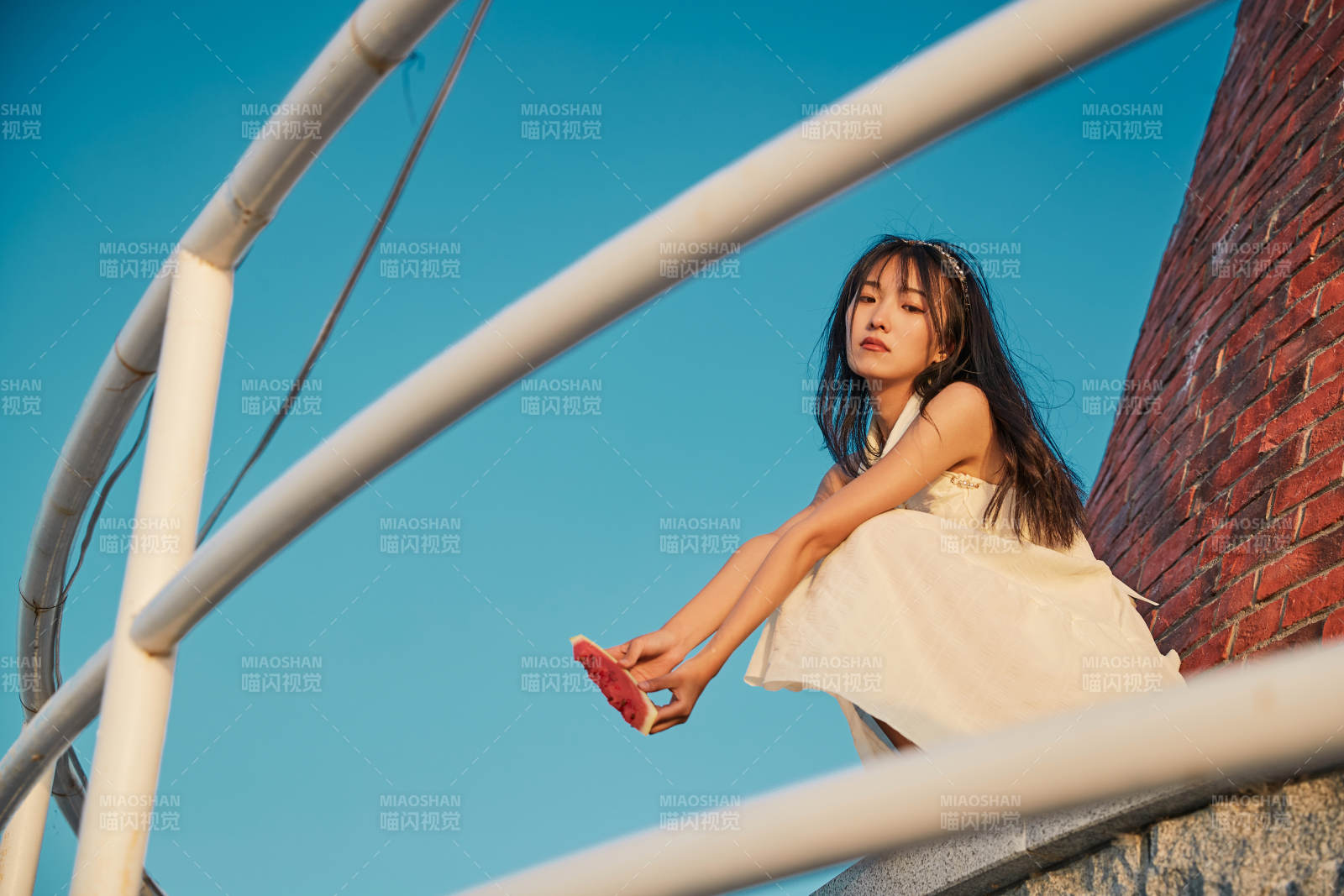 盛夏夕阳湖边码头灯塔上吃西瓜的少女图片