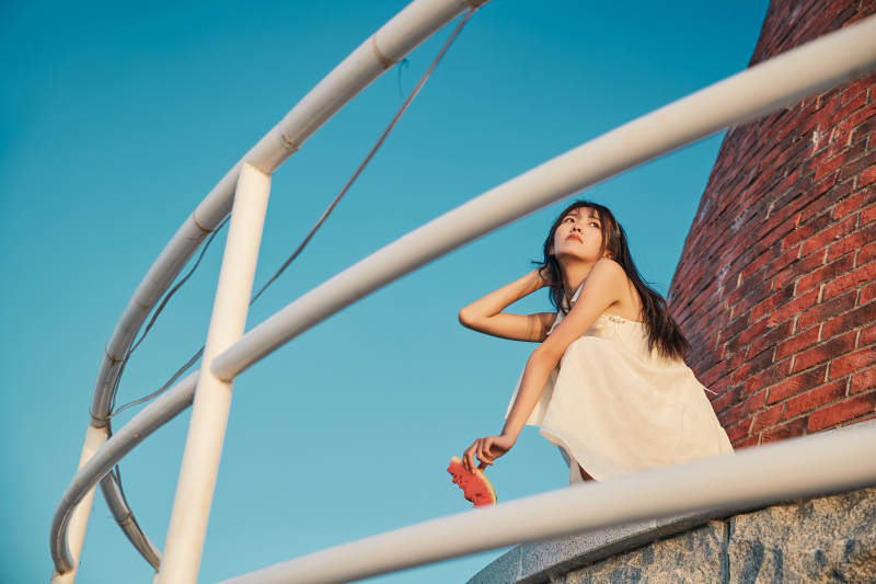 盛夏夕阳湖边码头灯塔上吃西瓜的少女图片