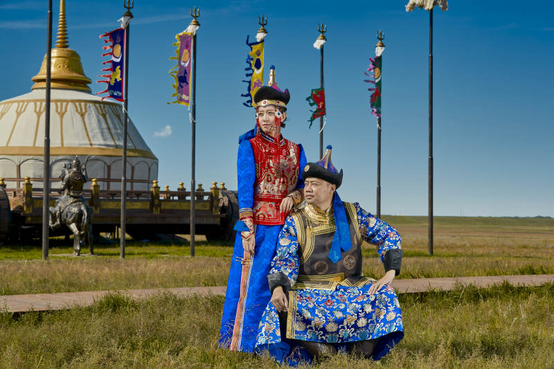 草原上蒙古包前穿蒙古族传统服饰的年轻夫妻图片