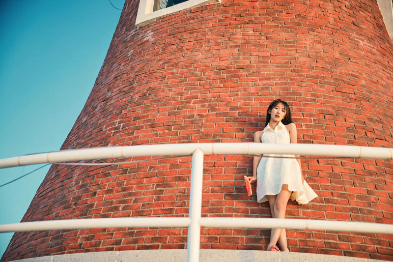 盛夏夕阳湖边码头灯塔上吃西瓜的少女图片