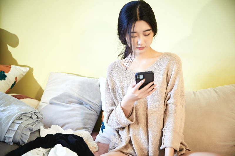 在沙发床上整理行装的年轻亚洲女性图片