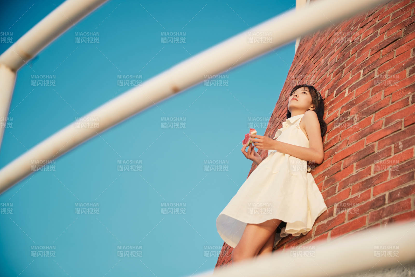 盛夏夕阳湖边码头灯塔上吃西瓜的少女图片