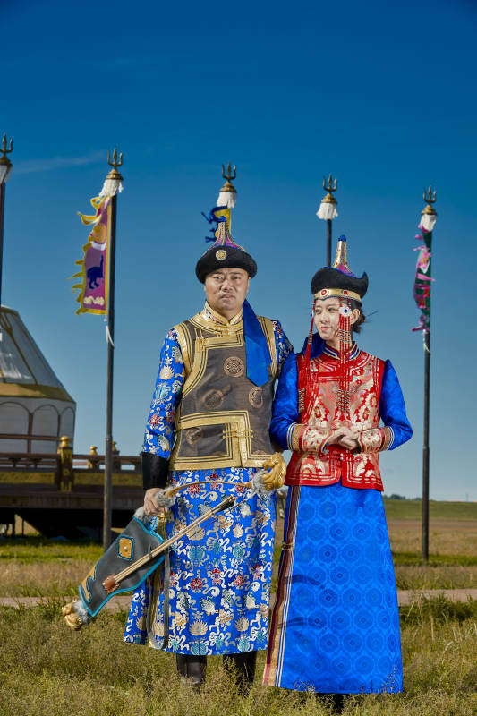 草原上蒙古包前穿蒙古族传统服饰的年轻夫妻图片