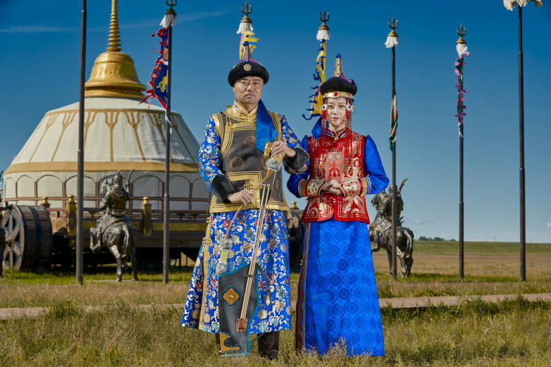 草原上蒙古包前穿蒙古族传统服饰的年轻夫妻图片