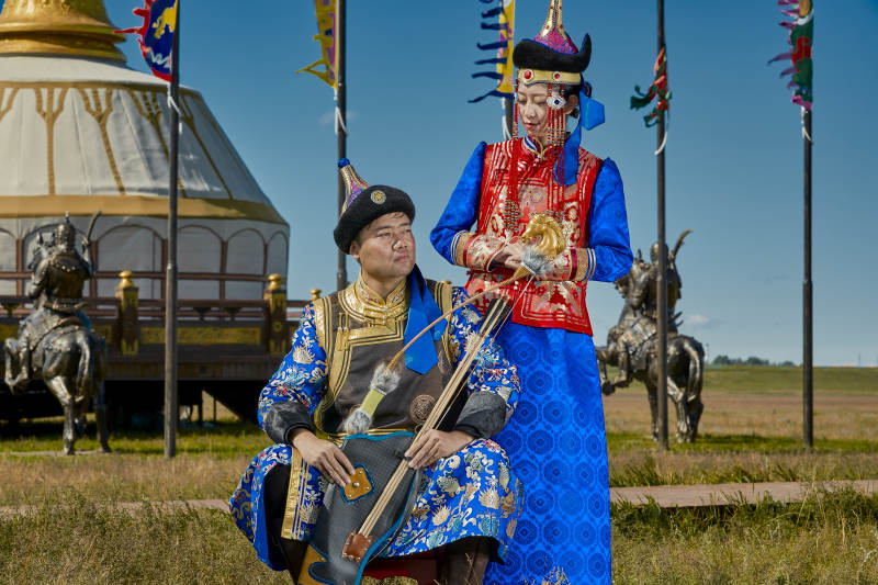 草原上蒙古包前穿蒙古族传统服饰的年轻夫妻图片